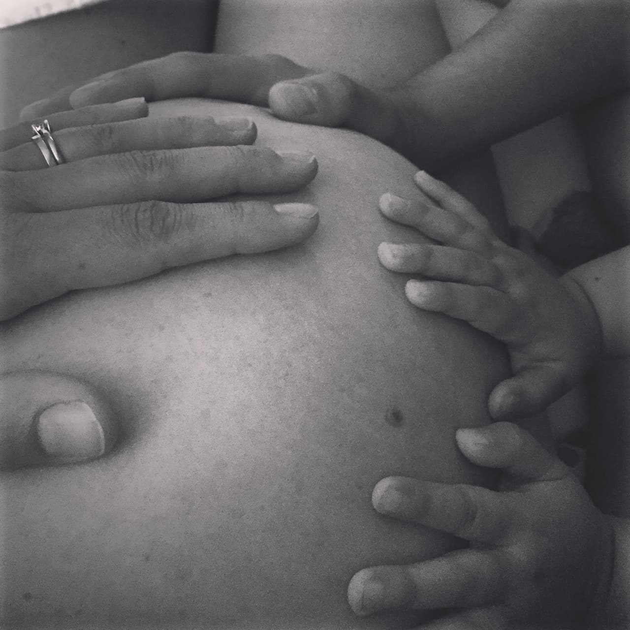 ventre rond d'une femme enceinte qui prépare un avac avec les mains du papa de la maman et de la future grande soeur